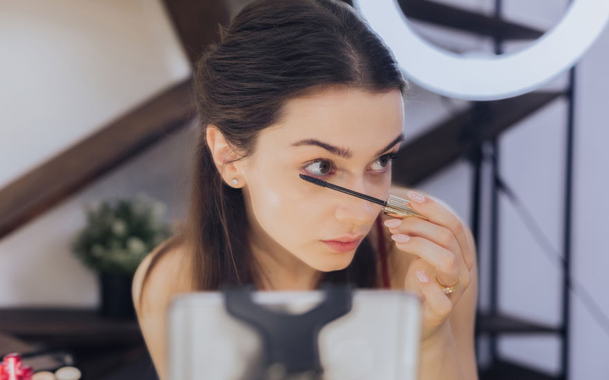 frau tuscht wimpern vor handykamera