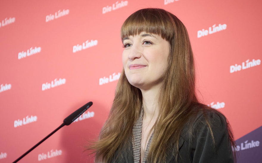 Politikerin Heidi Reichinnek lächelt und steht vor einer Wand mit dem Schriftzug "Die Linke"