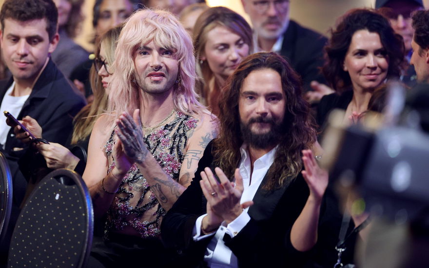 Bill und Tom Kaulitz sitzen im Publikum und klatschen mit ernster Miene