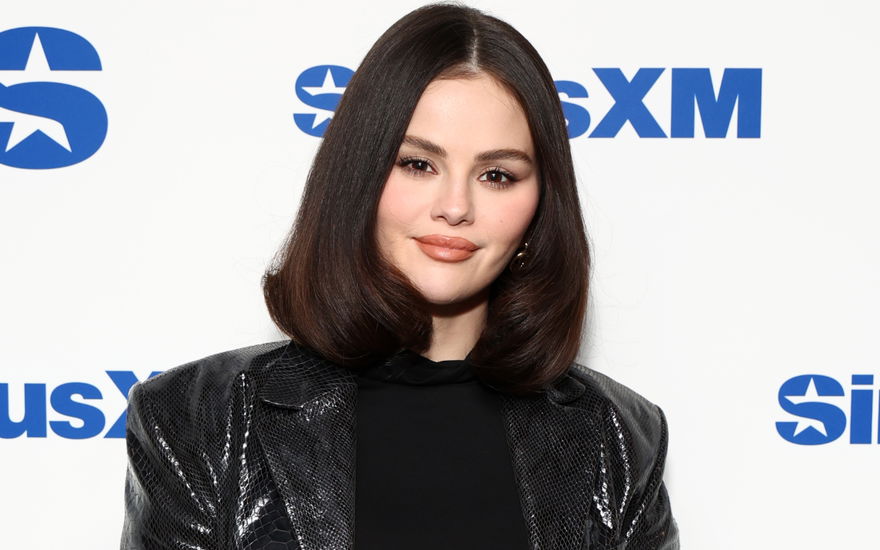 Selena Gomez vor weißer Wand mit Schrift