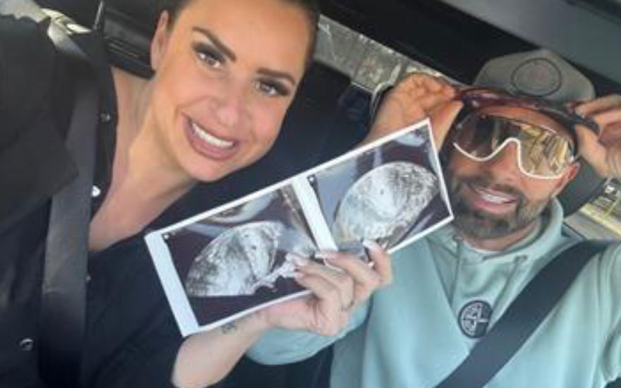 Virginia Weiß und Ehemann Andrew lächeln und zeigen ein Ultraschallbild