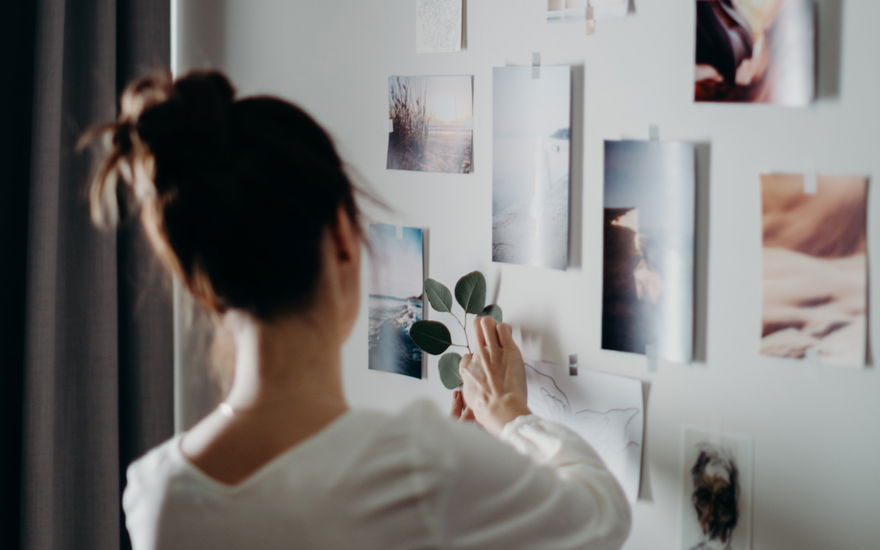 Frau klebt Bilder an ihre Wand