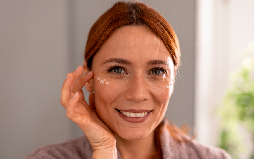 Rothaarige Frau mit Augencreme