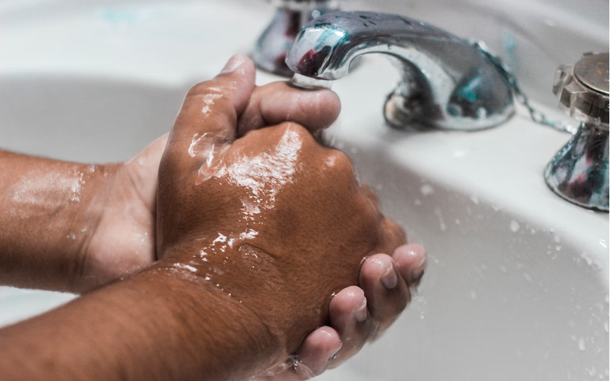 Hände werden am Waschbecken gewaschen