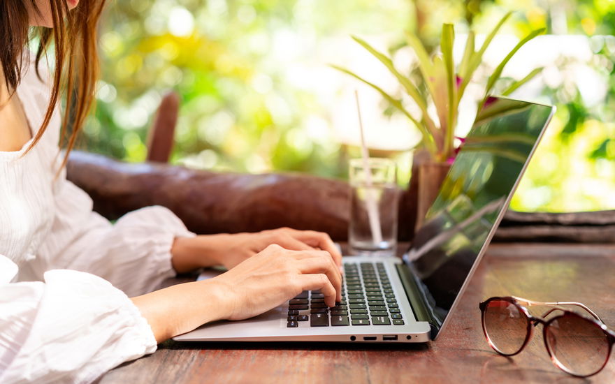 Junge Frau arbeitet im Urlaub am Laptop