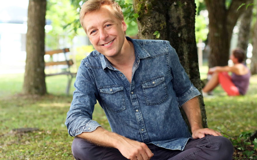 Max Müller sitzt lächelnd auf Stein im Park