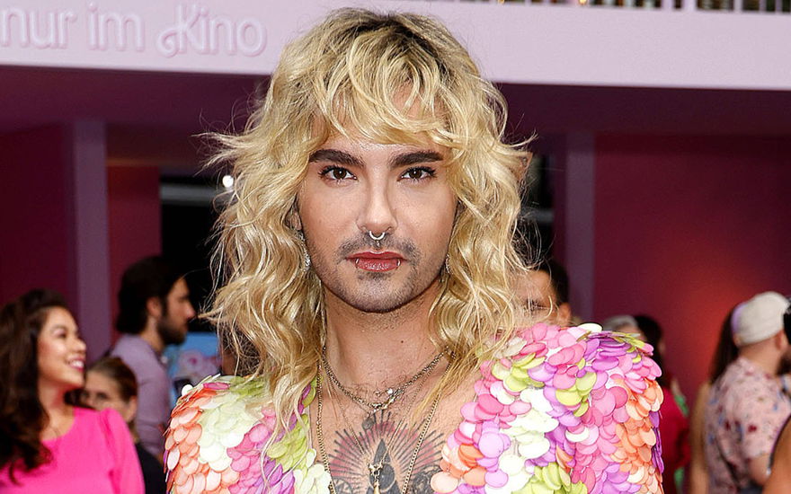 Bill Kaulitz mit blonden locken vor pinker wand