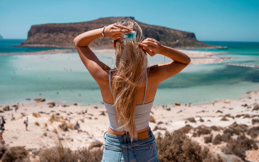Frau mit langen Haaren blickt aufs Meer
