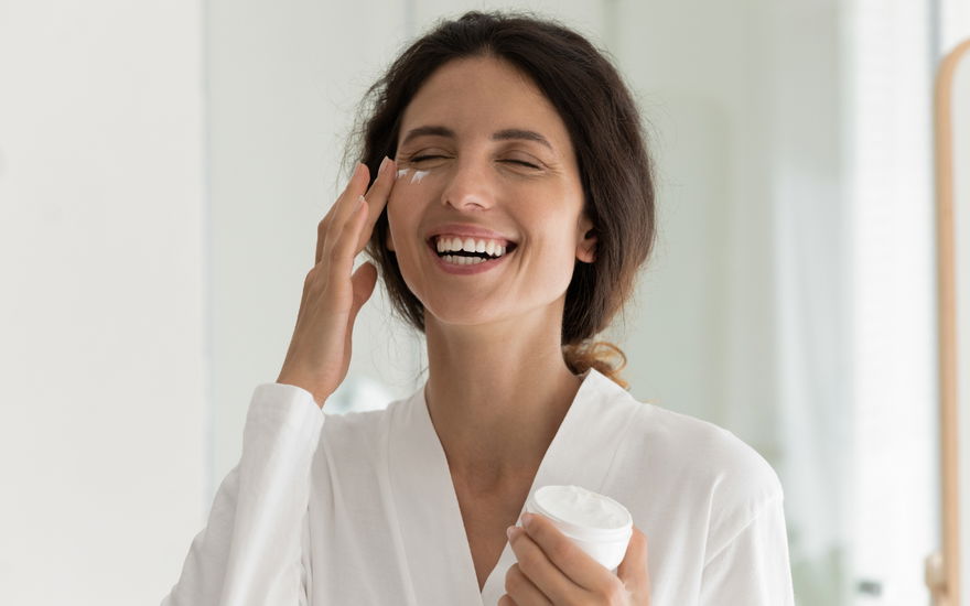 Frau trägt lachend Anti-Aging-Creme auf