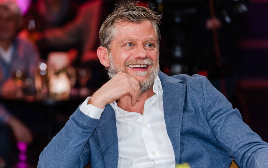 Andreas Guenther guckt lachend zur Seite, Hand am Kinn