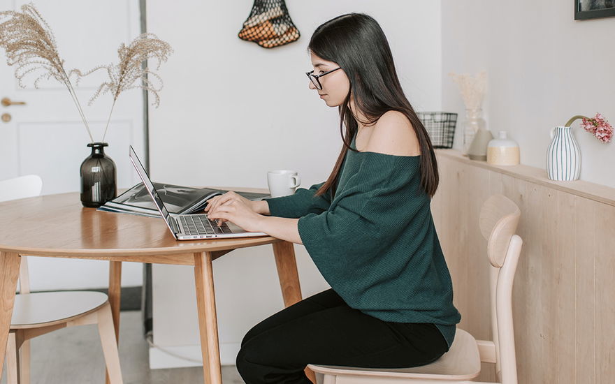 Eine Frau sitzt an ihrem Laptop und recherchiert online