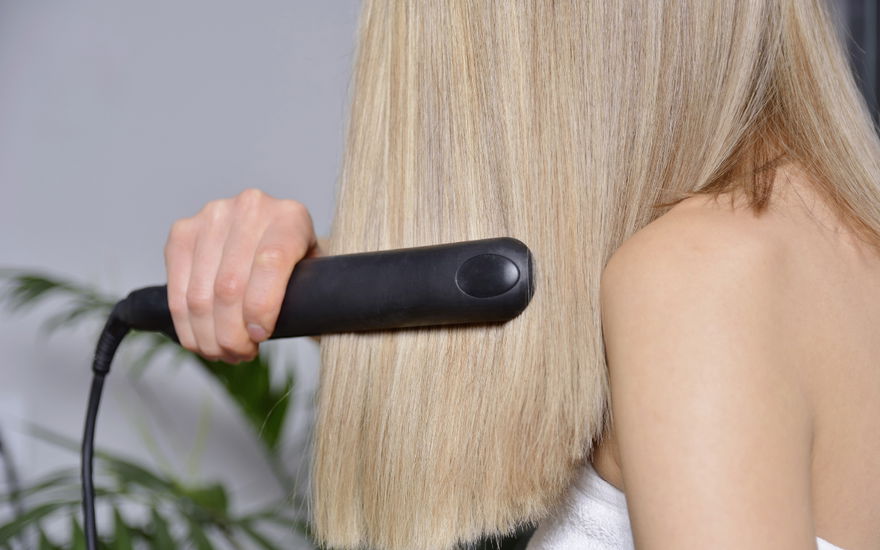 Frau glättet Haare
