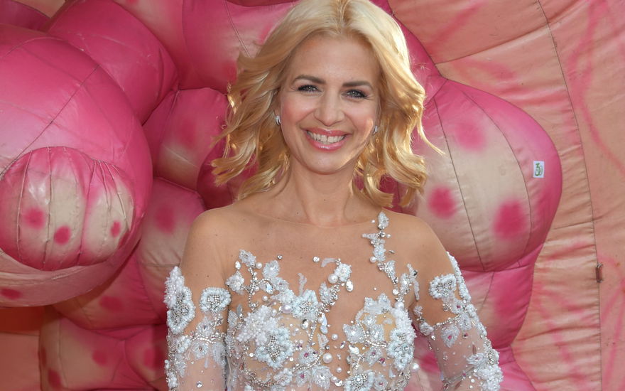 Susan Sideropoulos im weißen Glamour-Kleid, pinker Hintergrund