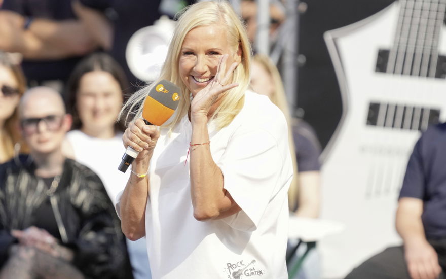 Andrea Kiewel lacht mit Hand am Mund