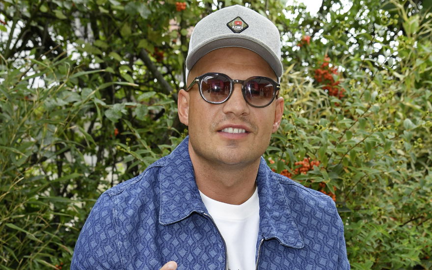 Pietro Lombardi lächelt mit Sonnenbrille vor grünen Büschen