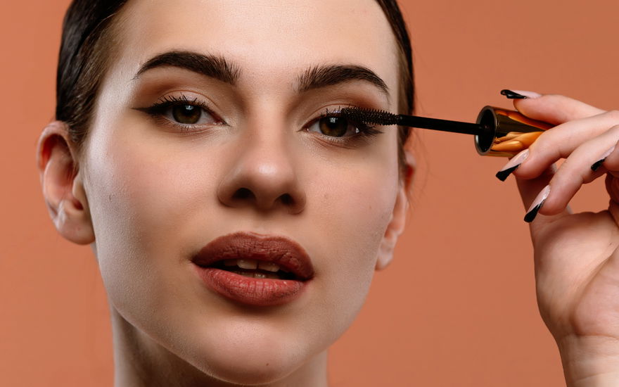 Frau mit Abend-Make-up trägt Mascara auf