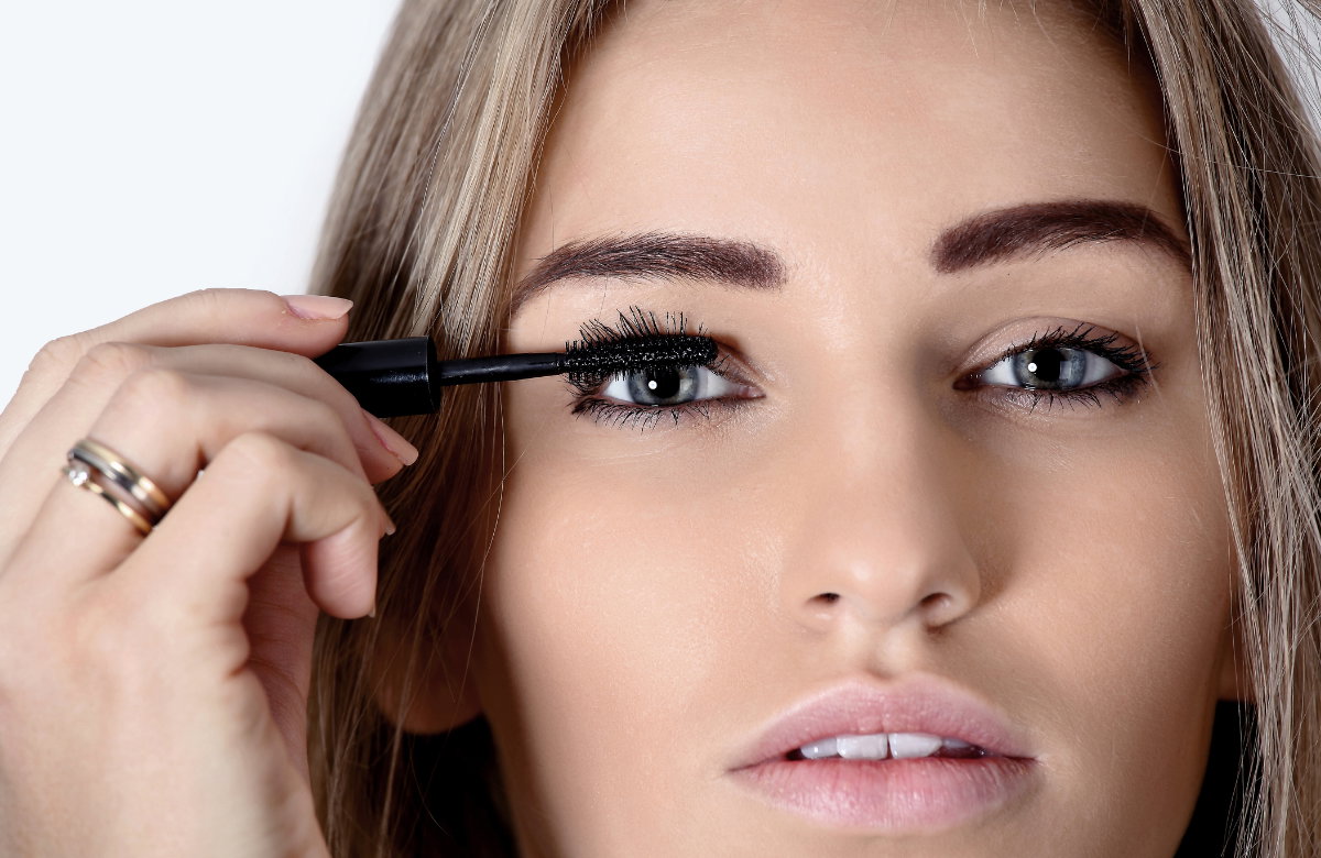 Frau mit langen Wimpern trägt Mascara auf