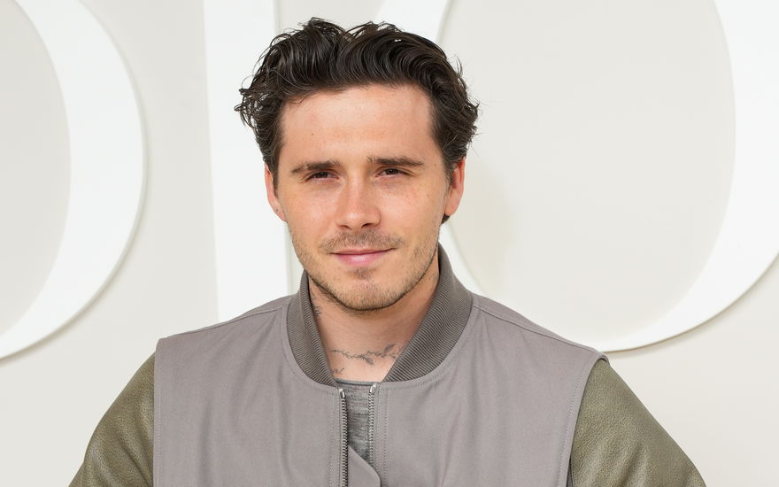 Brooklyn Beckham lächelt leicht, heller Hintergrund