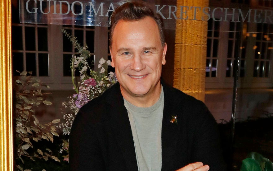 Guido Maria Kretschmer lächelt vor Blumen-Bouquet