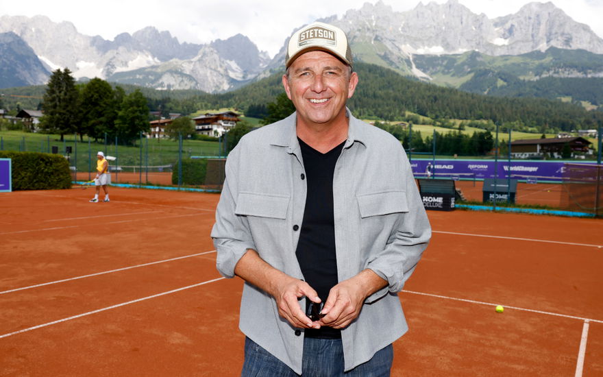Hans Sigl vor Bergkulisse auf Tennisplatz