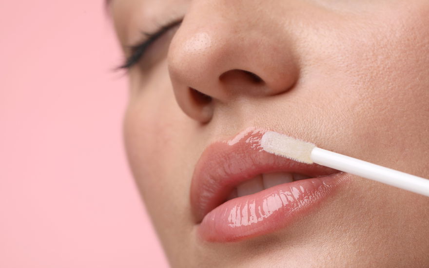 Frau mit vollen Lippen trägt Lipgloss auf