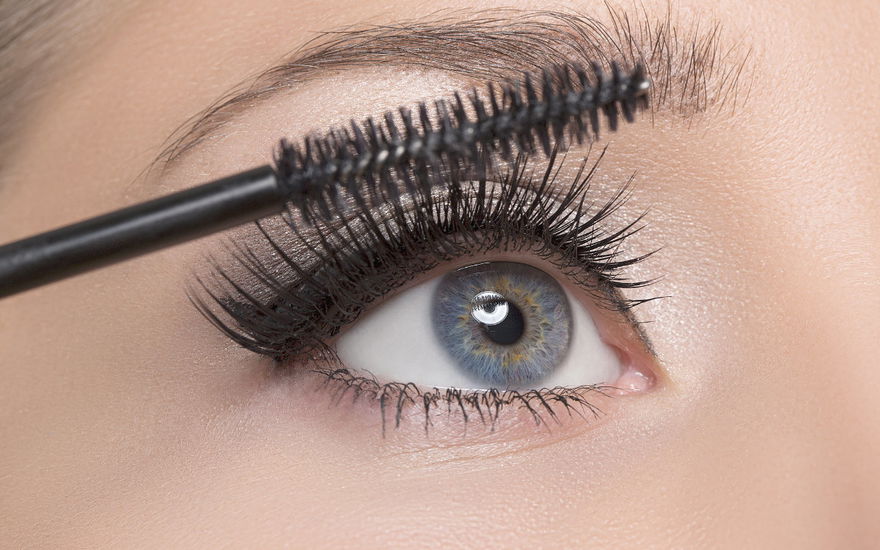 Frau mit blauen Augen benutzt Mascara