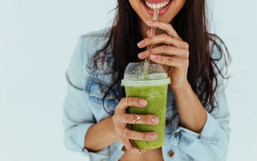 Eine Frau trinkt einen grünen Smoothie
