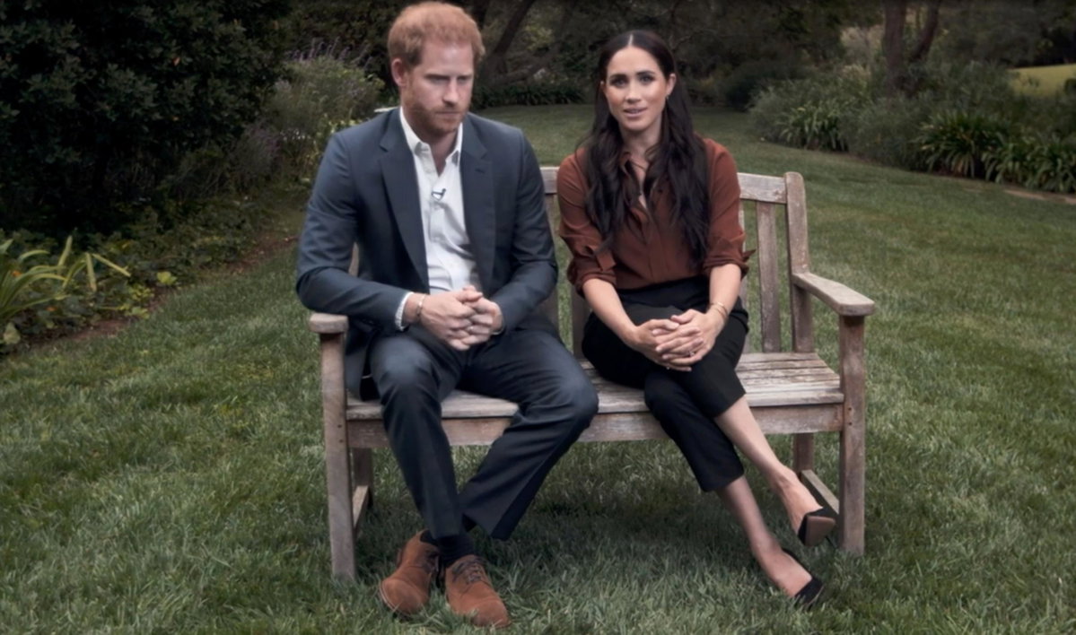 Prinz Harry und Herzogin Meghan sitzen gemeinsam auf einer Bank, schauen ernst