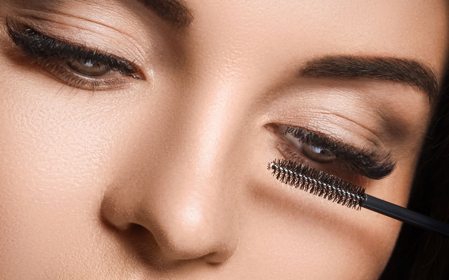 Frau tuscht lange Wimpern