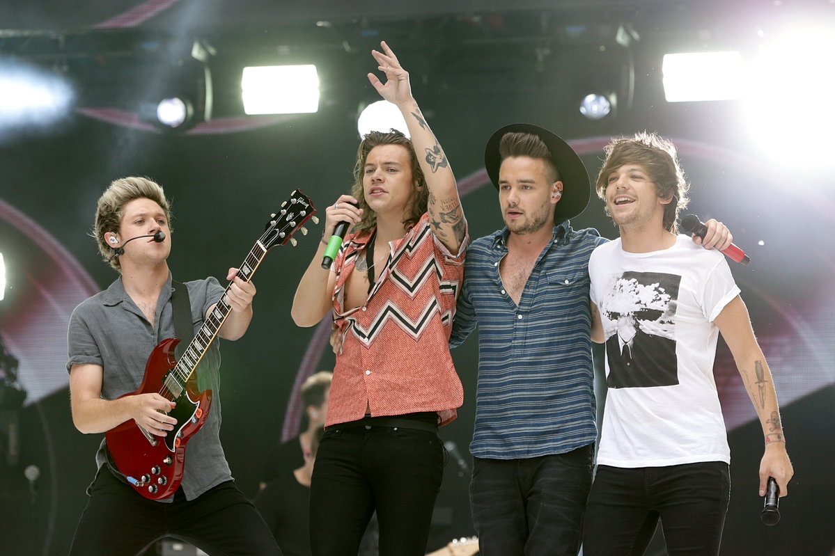 One Direction singen auf der Bühne, Niall Horan hält eine Gitarre in der Hand, Harry Styles ein Mikro