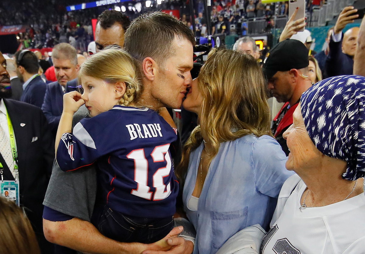 Tom Brady küsst Gisele Bündchen, er hat ihre gemeinsame Tochter auf dem Arm