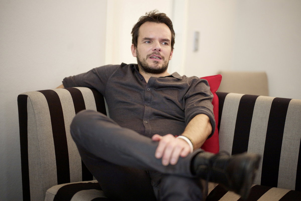 Steffen Henssler guckt zur Seite und sitzt auf einem Sessel