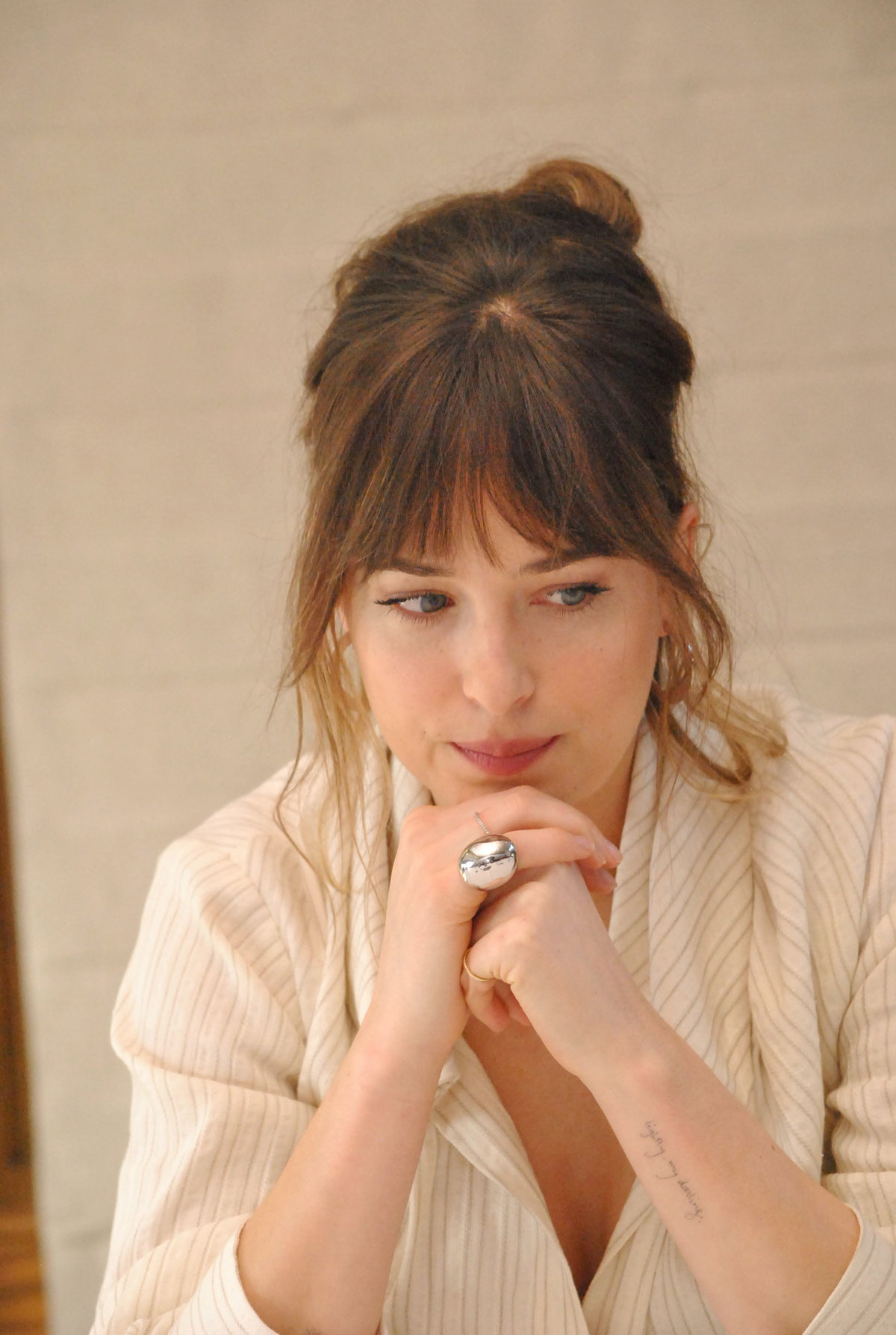 Dakota Johnson stützt Kopf auf Händen ab und sieht traurig zu Boden