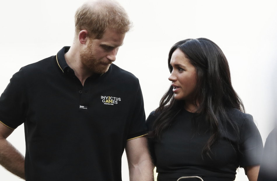 Prinz Harry sieht zu Boden, Herzogin Meghan sieht in fordernd an