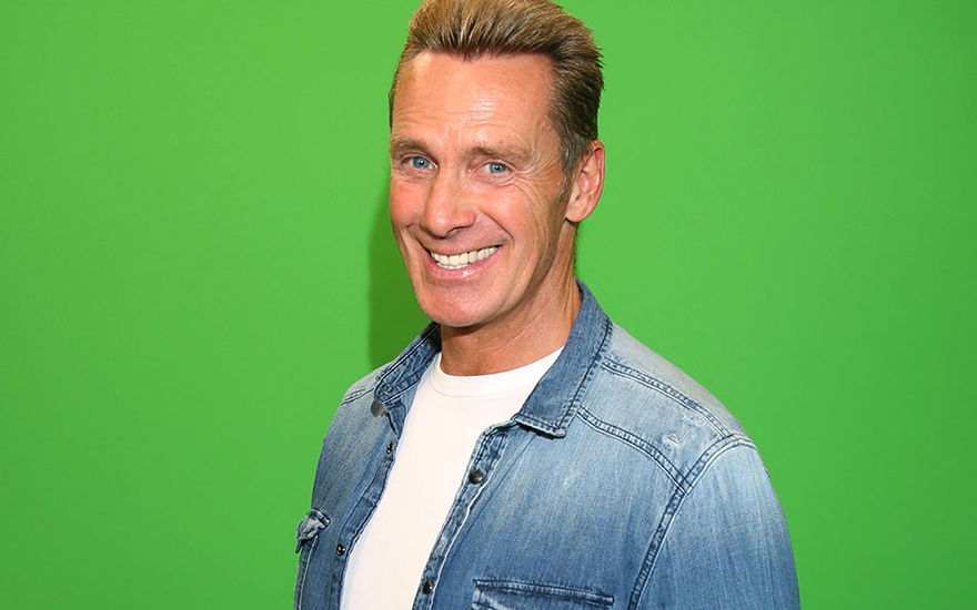 Jürgen Milski strahlt vor einer grünen Wand