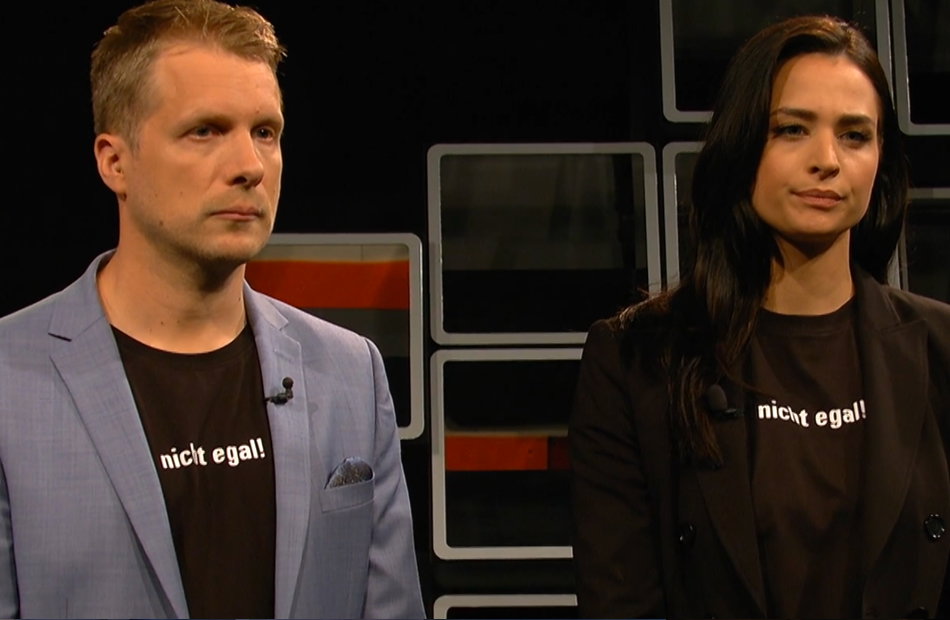 Oliver Pocher und Amira Pocher stehen mit Abstand zu einander und gucken streng.
