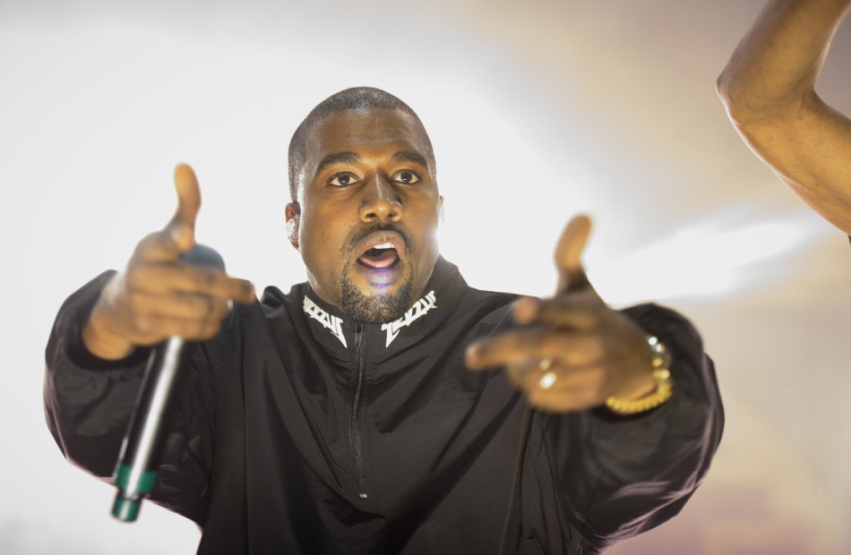 Kanye West mit Mikrofon und Fingerpistole.