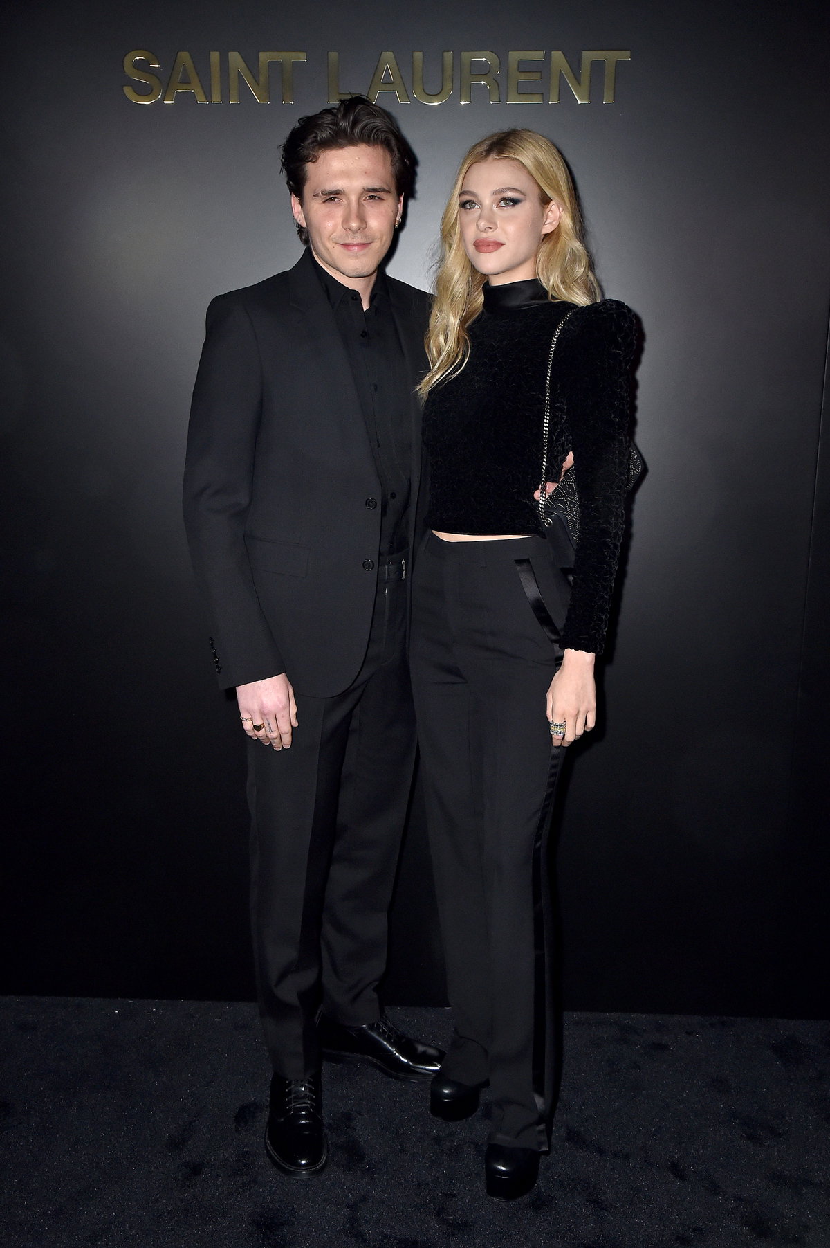 Brooklyn und Nicola Peltz-Beckham posieren vor einer schwarzen Wand