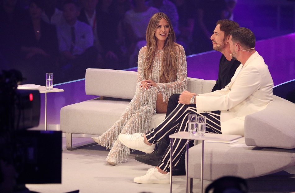 Heidi Klum, Thomas Hayo und Thomas Rath sitzen im GNTM-Finale auf einem weißen Sofa.