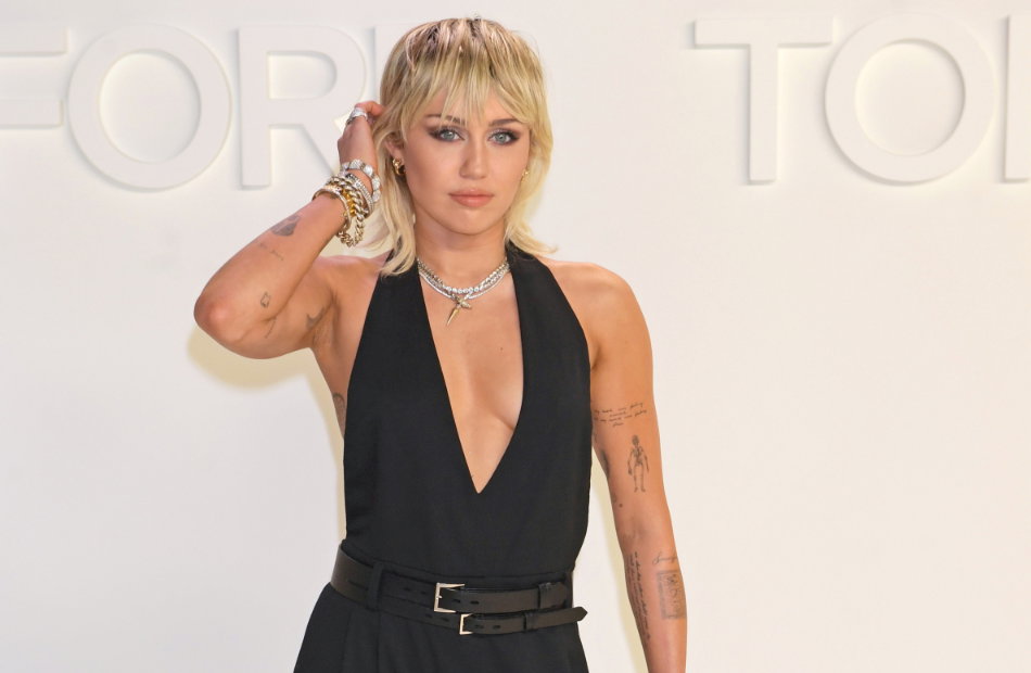 Miley Cyrus streift sich die Haare hinters Ohr