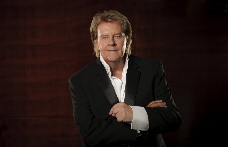 Howard Carpendale mit verschränkten Armen vor einem roten Hintergrund