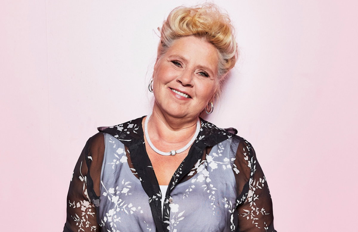 Silvia lächelnd vor rosa Hintergrund.
