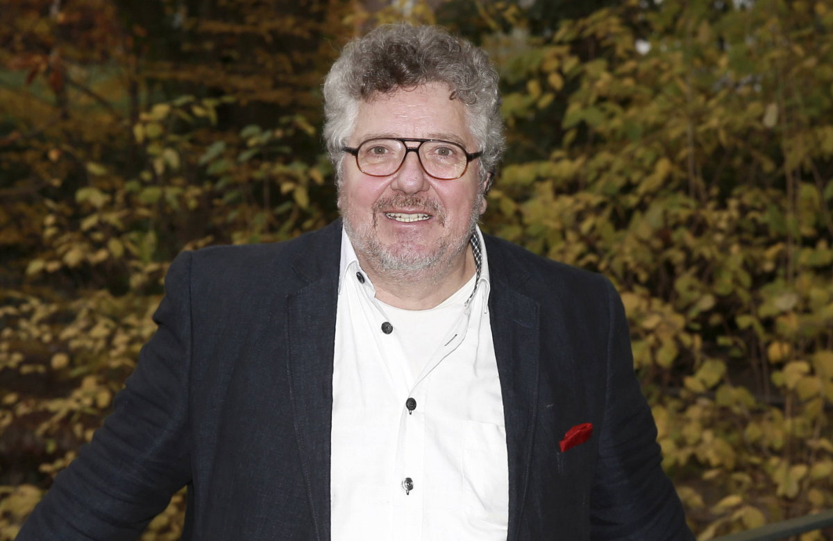 Michael Schanze im Anzug, Busch im Hintergrund