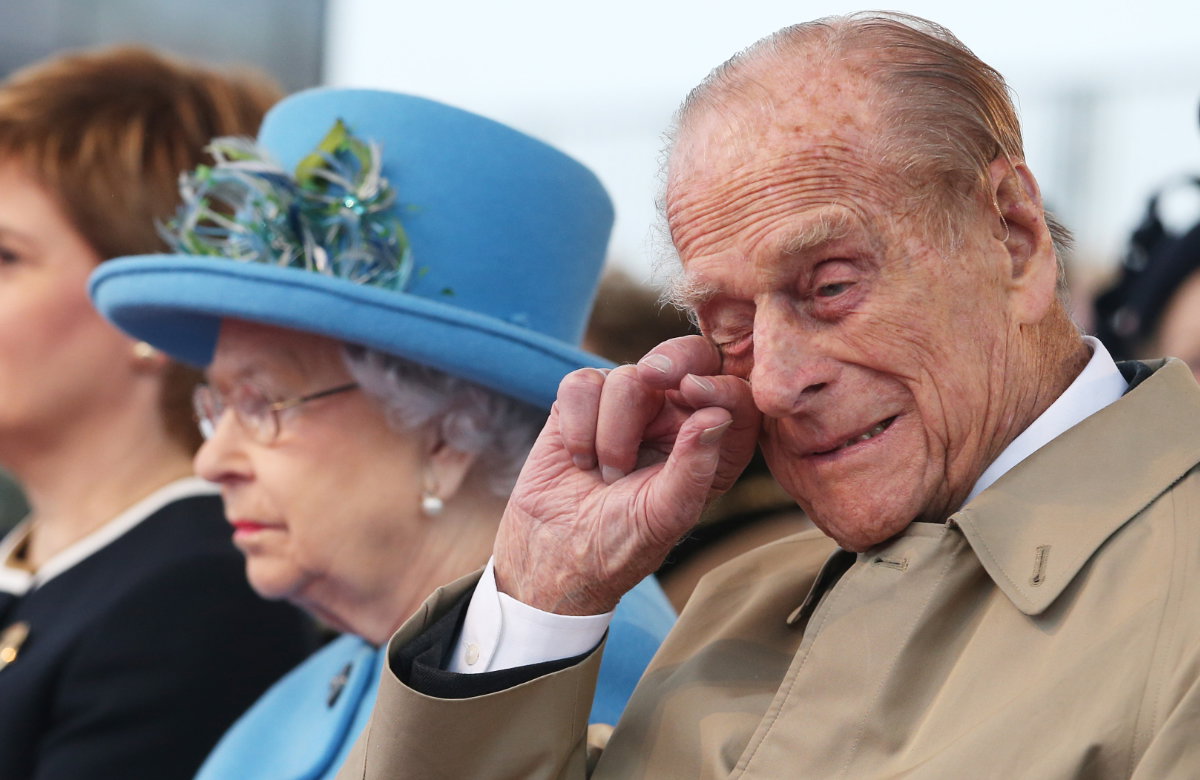 Philip wischt sich etwas aus dem Auge, Queen sitzt neben ihm
