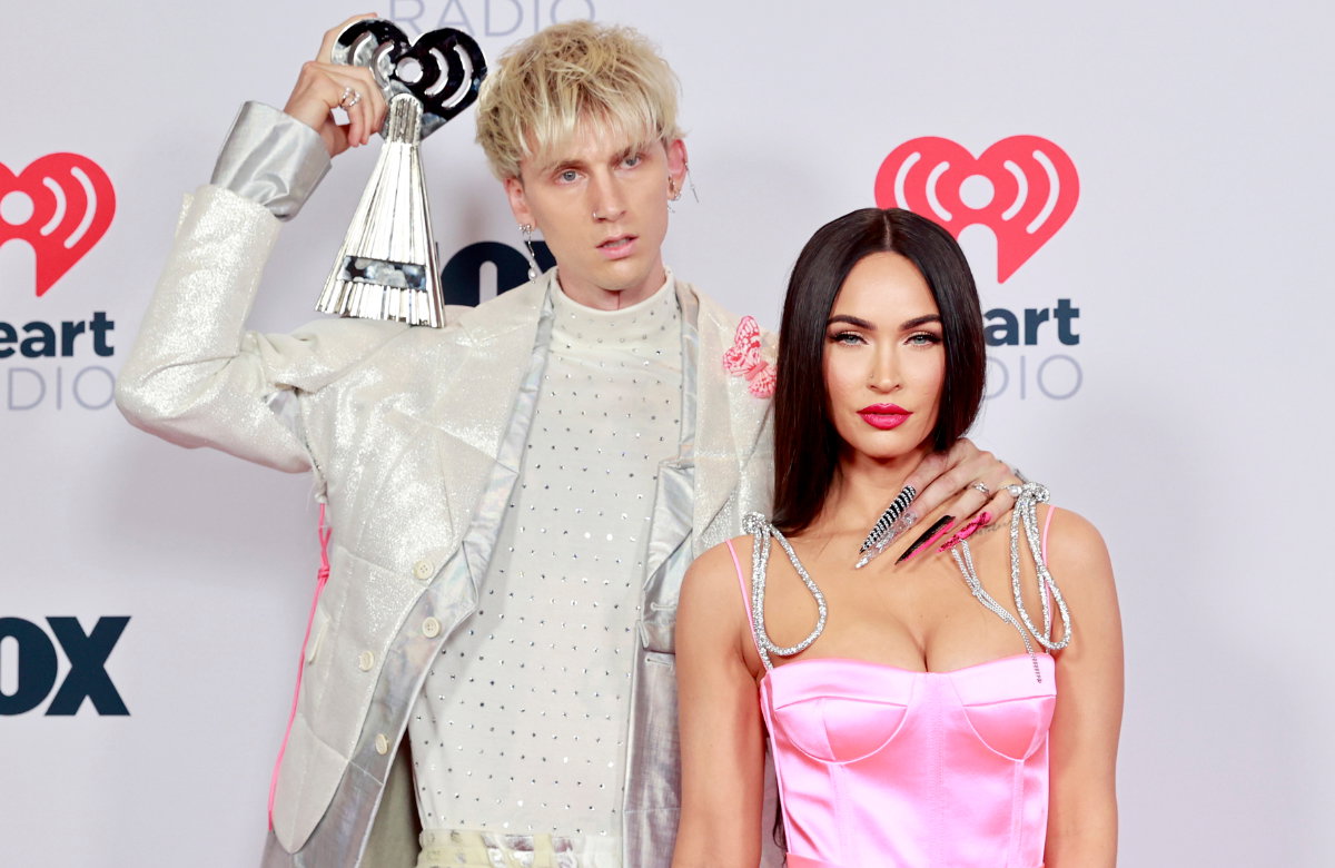 Machine Gun Kelly hält einen Award auf der Schulter, Megan Fox steht im rosanen Kleid neben ihm