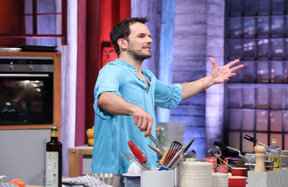 Steffen Henssler hebt die Hand bei "Grill den Henssler" und steht am Herd