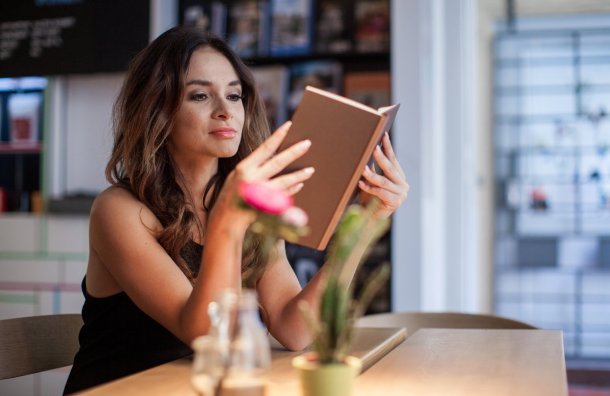 Frau liest ein Buch in einem Café