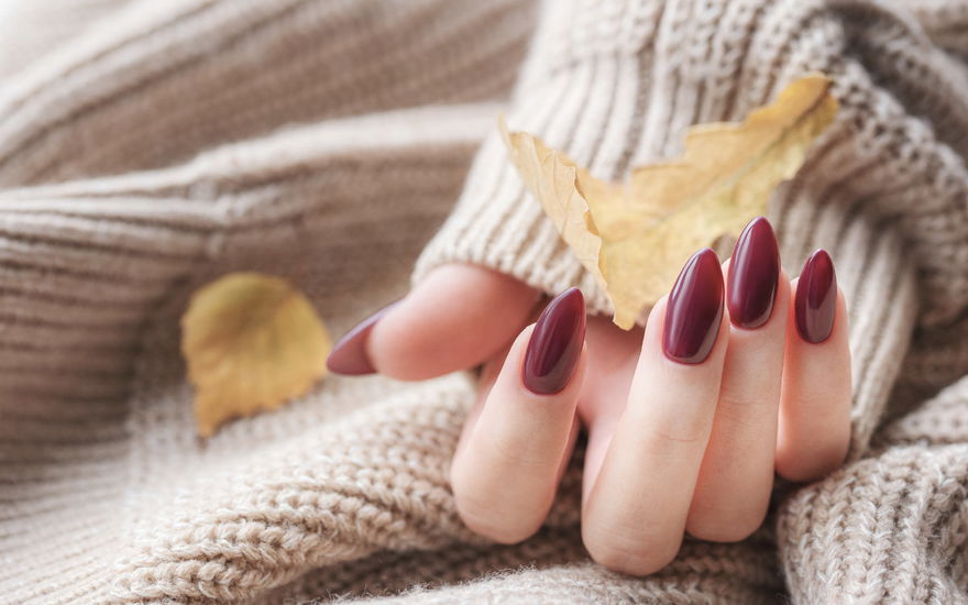Cherry Cola Nails – Frau mit weinroten Nägeln und Laub
