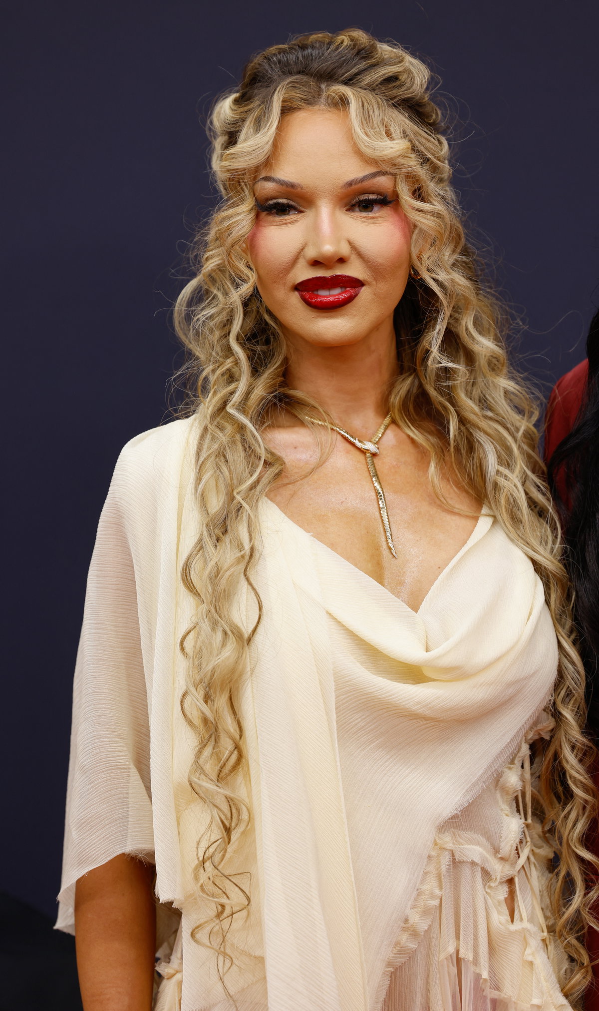 Shirin David lächelt mit roten Lippen und Locken